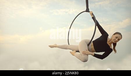 Frau in Sportkleidung, die am Abend, wenn die Sonne unterging, Sky Yoga auf dem Dach macht. Selbstversorgung und Gesundheitskonzepte. Stockfoto