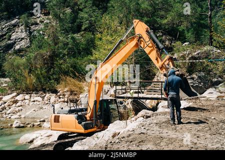 Schwere Maschinen Dragline Bagger graben Boden in der Bergschlucht. Bagger ditcher arbeitet an einer Goldmine in den Bergen. Bergbauausrüstung Stockfoto