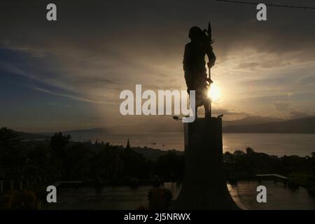 Silhouette der 8 Meter hohen Statue von Martha Christina Tiahahu (1800-1818), einer Heldin, die für ihre Rolle während der Kämpfe gegen die Kolonialherrin im 19.. Jahrhundert bekannt ist. Das Denkmal befindet sich auf dem Karangpanjang Hügel mit Blick auf die Stadt Ambon, die Bucht von Ambon und die Banda See in Zentral-Maluku, Maluku, Indonesien. Stockfoto