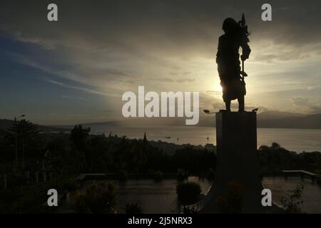 Silhouette der 8 Meter hohen Statue von Martha Christina Tiahahu (1800-1818), einer Heldin, die für ihre Rolle während der Kämpfe gegen die Kolonialherrin im 19.. Jahrhundert bekannt ist. Das Denkmal befindet sich auf dem Karangpanjang Hügel mit Blick auf die Stadt Ambon, die Bucht von Ambon und die Banda See in Zentral-Maluku, Maluku, Indonesien. Stockfoto