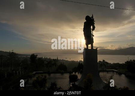 Silhouette der 8 Meter hohen Statue von Martha Christina Tiahahu (1800-1818), einer Heldin, die für ihre Rolle während der Kämpfe gegen die Kolonialherrin im 19.. Jahrhundert bekannt ist. Das Denkmal befindet sich auf dem Karangpanjang Hügel mit Blick auf die Stadt Ambon, die Bucht von Ambon und die Banda See in Zentral-Maluku, Maluku, Indonesien. Stockfoto