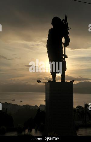 Silhouette der 8 Meter hohen Statue von Martha Christina Tiahahu (1800-1818), einer Heldin, die für ihre Rolle während der Kämpfe gegen die Kolonialherrin im 19.. Jahrhundert bekannt ist. Das Denkmal befindet sich auf dem Karangpanjang Hügel mit Blick auf die Stadt Ambon, die Bucht von Ambon und die Banda See in Zentral-Maluku, Maluku, Indonesien. Stockfoto