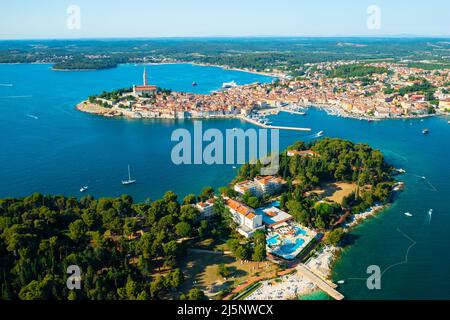 Umgebung von Rovinj mit der Kirche der heiligen Euphemia in der Nähe der Adria. Villen mit Pools und Gebäuden mit roten Dächern bei hellem Sonnenlicht. Luftaufnahme Stockfoto