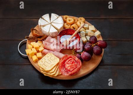 Vorspeisen-Tafel mit verschiedenen Käsesorten, Fleisch, Wurstrosette, Traubengebäck und salzigen Keksen. Aufschnitt und Käseplatte. Draufsicht Stockfoto