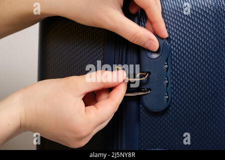 Eine Hand und ein Kombinationsschloss am Koffer. Reißverschluss-Schiebeverriegelung, Nahaufnahme. Stockfoto