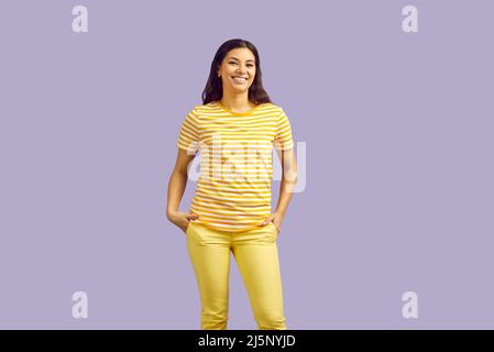 Glücklich schöne junge Frau in lässigen Kleidern stehend isoliert auf lila Hintergrund Stockfoto