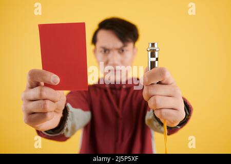 Fußballschiedsrichter mit roter Karte und Pfeife, Fokus auf den Vordergrund Stockfoto