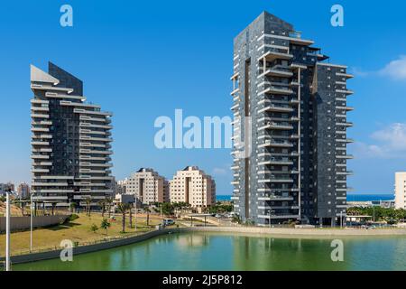 Kleiner künstlicher See und moderne Hochhäuser unter blauem Himmel in Ashdod, Israel. Stockfoto
