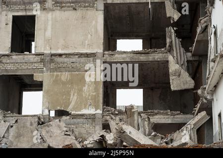 Ein zerstörtes Gebäude in Nahaufnahme mit einem Stapel von Betonschutt, Platten und Pfählen im Vordergrund. Hintergrund. Stockfoto