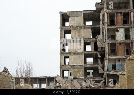 Ein zerstörtes Gebäude vor einem grauen Himmel mit Betonschutt-Haufen und hervorstehenden Pfählen im Vordergrund. Hintergrund. Stockfoto