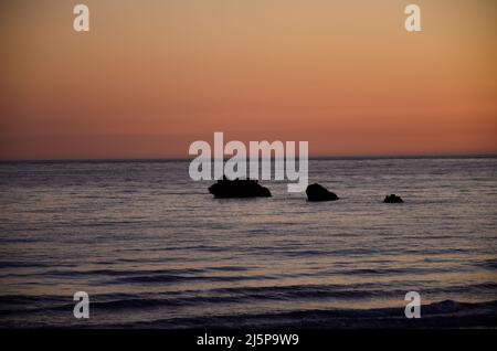 Farbiger Himmel bei Sonnenuntergang an der Küste von Conil in Spanien, mit Blick auf zwei große Felsen im Atlantischen Ozean Stockfoto