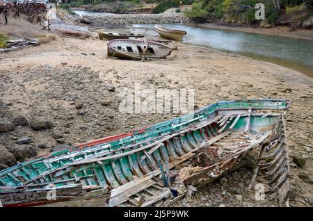 Schiffsfriedhof mit alten, kaputten, hölzernen Fischerbooten, die bei Ebbe auf dem Sand neben der Atlantikküste liegen Stockfoto