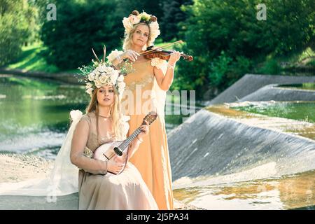 Duett von Frauen, die in der Natur Gitarre und Violine spielen Stockfoto