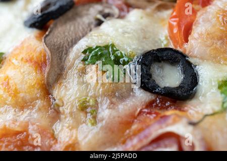 Makroaufnahme von italienischer Pizza mit Mozzarella und Kirschtomaten, Pilzen und roten Zwiebeln, Gewürzen, Ketchup und Paprika. Italienische Küche. Stockfoto