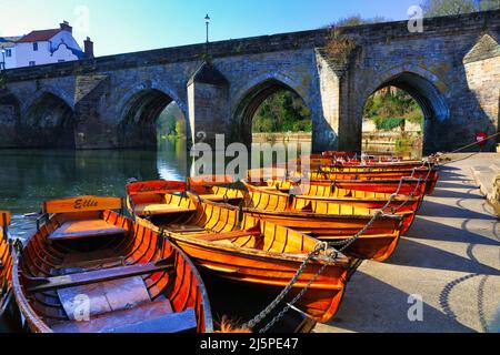 Ruderboote liegen am Flussufer mit der Elvet Bridge im Hintergrund. Durham City, County Durham, England, Großbritannien. Stockfoto