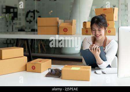 Porträt einer asiatischen jungen Frau KMU arbeiten mit einer Box zu Hause am Arbeitsplatz. Startup Kleinunternehmer, Kleinunternehmer KMU oder freiberuflich Stockfoto