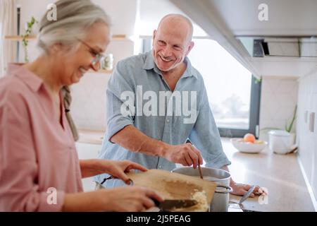 Glückliches Seniorenpaar, das zu Hause zusammen kocht. Stockfoto