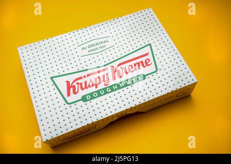 London, Vereinigtes Königreich, 21.. März 2022:- Eine Kiste mit Krispy Kreme Donuts auf gelbem Hintergrund Stockfoto
