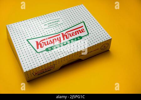London, Vereinigtes Königreich, 21.. März 2022:- Eine Kiste mit Krispy Kreme Donuts auf gelbem Hintergrund Stockfoto
