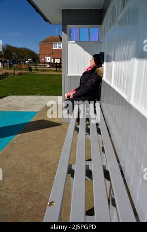 Ältere Frau dösiert im sonnendurchfluteten Küstenschutzgebiet mundesley norfolk england Stockfoto