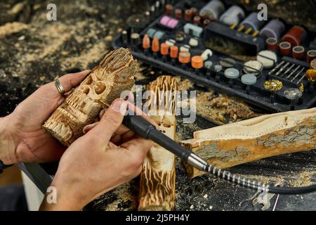 Nahaufnahme der männlichen Hände mit Power-Holz-Arbeitswerkzeuge Graver, Schnitzen Stockfoto