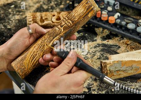 Nahaufnahme der männlichen Hände mit Power-Holz-Arbeitswerkzeuge Graver, Schnitzen Stockfoto
