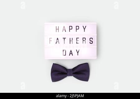 Happy Fathers Day - Zitat. Fliege und Leuchtkasten auf blauem pastellfarbenem Hintergrund. Stockfoto