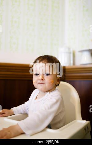 Lächelndes kaukasisches Baby, das auf einem Stuhl sitzt und ihren Geburtstag feiert Stockfoto