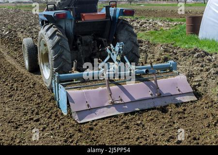 Der Traktor lockert und kultiviert den Boden auf dem Feld. Stockfoto