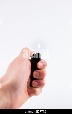 Ein Gasfeuerzeug in der Hand brennt Feuer auf weißem Hintergrund Stockfoto