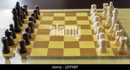 Schachbrett mit weißen und braunen Schachfiguren aus Holz, die auf dem Tisch stehen Stockfoto