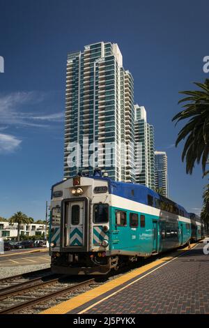 Der Zug fährt auf dem Santa Fe Depot vor einigen hohen Wohntürmen in der Innenstadt von San Diego Stockfoto