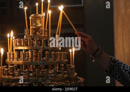 Gläubige zünden Kerzen während eines Gottesdienstes in Athen an. Die Griechen feiern Ostern am Sonntag, dem 24. April, dem wichtigsten religiösen Feiertag im orthodoxen christlichen Kalender, zum ersten Mal seit zwei Jahren, ohne irgendwelche Einschränkungen im Zusammenhang mit dem Coronavirus für die Teilnahme an religiösen Gottesdiensten oder für die Anzahl der Personen, die sich versammeln können. Stockfoto