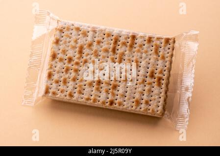 Ungesäuertes Matzo in versiegelter Verpackung, Brot für Pesach, jüdischer Passahfeiertag. Matzah-Fladenbrote auf hellbraunem Hintergrund Stockfoto