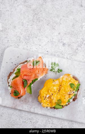 Rührei mit geräuchertem Lachs, Frischkäse und Avocado auf Toast Stockfoto