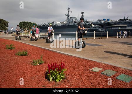 Gruppe von Touristen, die Segways vor dem USS Midway Flugzeugträger, San Diego Navy Pier, reiten Stockfoto