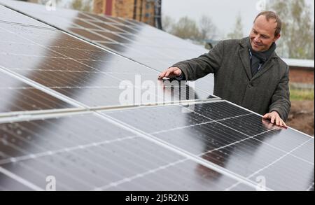 25. April 2022, Sachsen, Zwickau: Wolfram Günther (die Grünen), Sachsens Energie- und Klimaschutzminister, steht in einem neuen Solarpark. Die Enerparc AG betreibt den sechs Hektar großen Solarpark Mosel und wird in den nächsten 20 Jahren jährlich 5,5 Millionen kWh Solarenergie für die Produktion der vollelektrischen Volkswagen-Modelle aus Zwickau liefern. Alle drei Volkswagen-Standorte in Sachsen werden bereits seit Ende 2017 mit Ökostrom aus Wasserkraft versorgt. Bisher kam dies jedoch aus Österreich. Zwickau ist nun der erste sächsische Standort, der Solarenergie für die Fahrzeugproduktion erhält Stockfoto