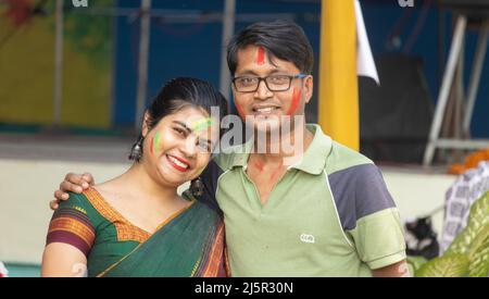 Ein indisches Paar mit bunten Gesichtern, das in holi - dem Fest der Farben - die Kamera anschaut Stockfoto