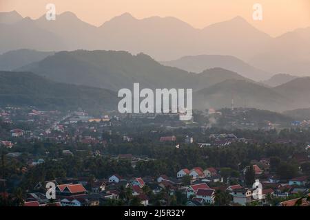 Ruhige Aussicht auf die antike Stadt Luang Prabang, umgeben von Bergen in der Abenddämmerung, ein Reiseziel in Laos und Südostasien. Stockfoto