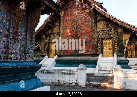 Außenansicht des alten buddhistischen Tempels im Wat Xieng Thong, goldene Gemälde, Buntglasdekoration an den Wänden, Holztüren. Luang Prabang, Laos. Stockfoto