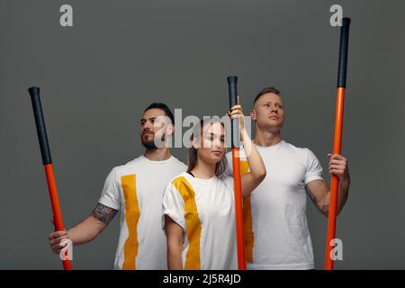 Menschen stehen zusammen und üben Stöcke. Karate-Meister posieren mit Stöcken im Studio zusammen. Stockfoto