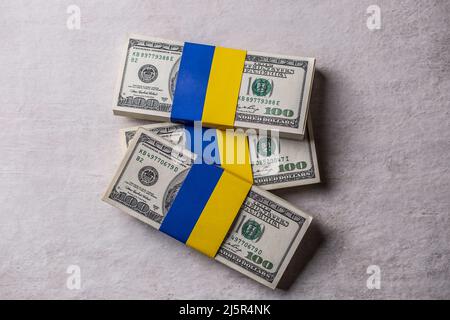 Geldbündel mit der ukrainischen Flagge gebunden. Das Konzept der Unterstützung der amerikanischen Regierung für die vom Krieg zerrissenen Stockfoto