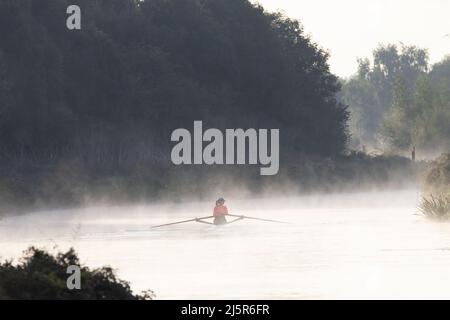 EXETER, Großbritannien – 25. SEPTEMBER 2018 Frau in einem Orange Top Rudertraining auf dem Exeter Schiffskanal am frühen Morgen mit Nebel auf dem Wasser Stockfoto