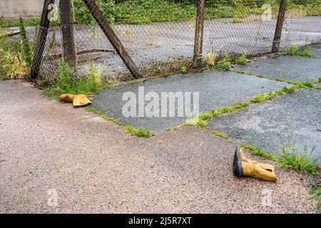 Ein Paar gelbe Rigger Stiefel wurde in der Hinterstraße der Stadt weggeworfen Stockfoto