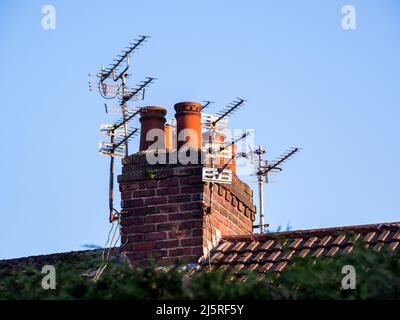 Mehrere Fernseher Ariel und Antenne auf dem Kamin Stapel eines Hauses Stockfoto