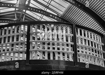 Ein geschwungener Balkon auf einer Bahnhofsfußliege. Ein Mann verhandelt einige Schritte und ein Oberlicht ist oben. Stockfoto