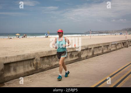 Frau, die am Strand auf dem Ocean Front Walk in Mission Bay, San Diego, läuft Stockfoto