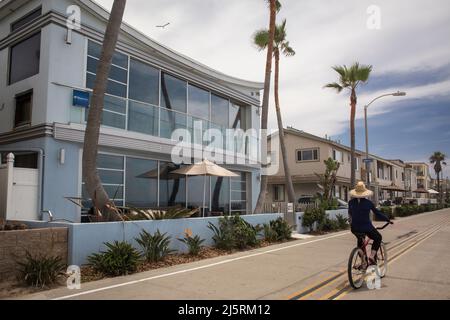 Frau, die vor einigen Sommerferienhäusern Fahrrad fährt, Strandpromenade, Mission Bay, San Diego Stockfoto