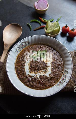 Dal makhni oder schwarze Linsensuppe in einer Schüssel zusammen mit Gewürzen serviert. Selektiver Fokus. Stockfoto