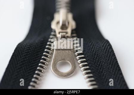 Nahaufnahme Makroaufnahme eines offenen schwarzen Messing-Reißverschlusses auf weißem Hintergrund isoliert Stockfoto